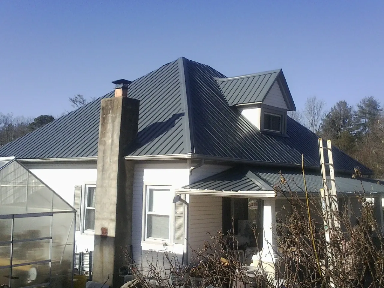 Dark blue standing seam metal roof on a white farmhouse with dormer — Slate & Tile Roof Repair by Roofing Brothers in Elsinore