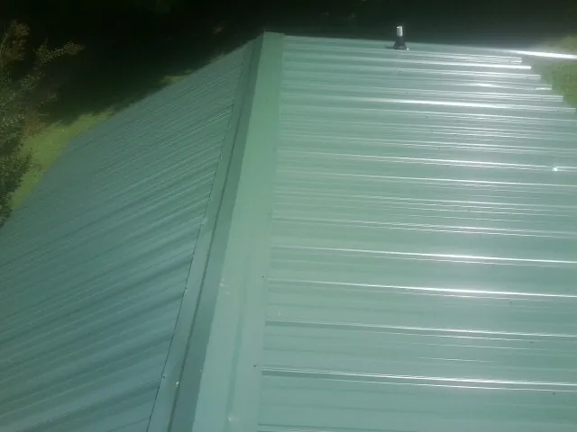 New green metal panels meeting at the ridge of a roof — Flat Roof Repair work by our crew in Elsinore