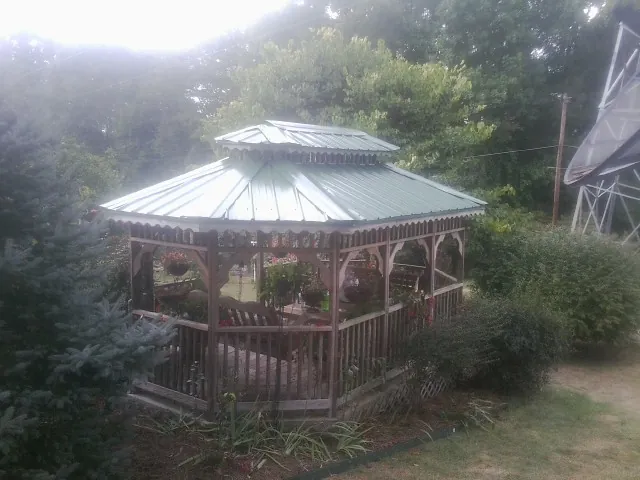 Green metal roof on a backyard gazebo surrounded by garden beds in Elsinore