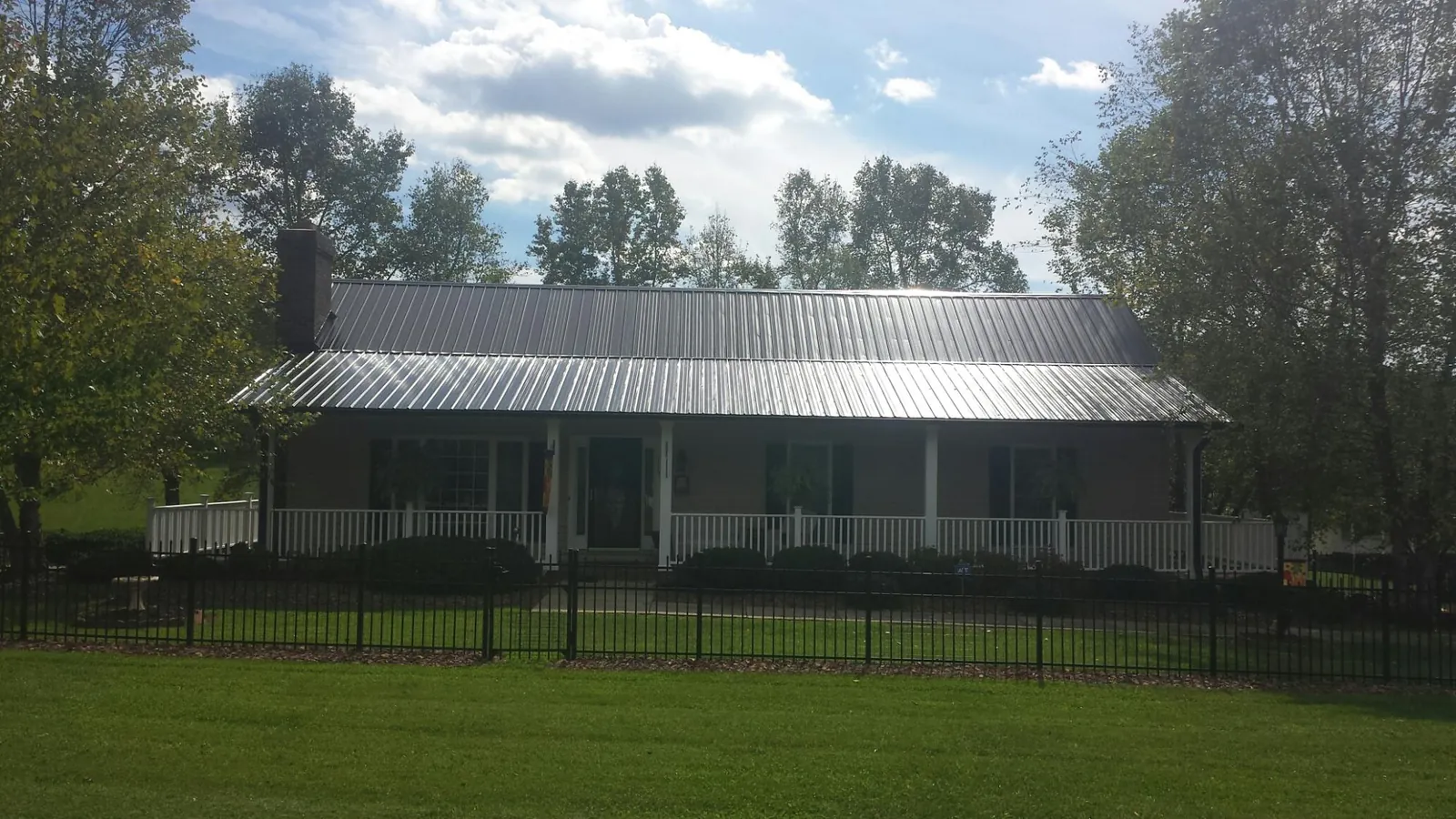 Gray metal roof on a brick ranch with a full width front porch — Gutter Guard Installation work by our crew in Elsinore