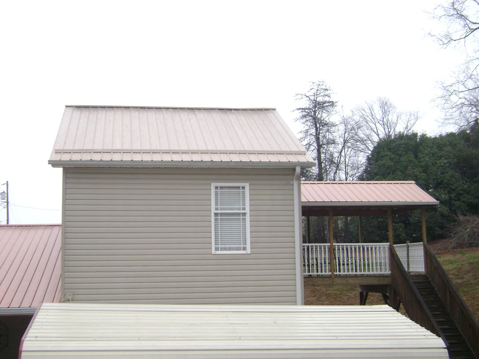Tan metal roofs on a two story addition and attached porch, from a Roof Replacement job in Elsinore