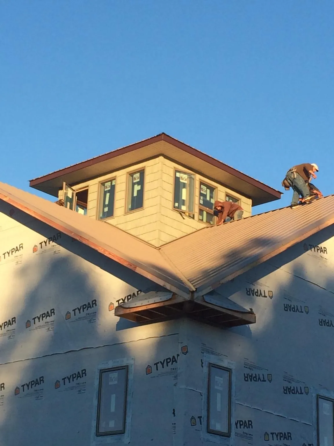 Roofers working around a rooftop cupola on a new metal roof at sunset — Roof Waterproofing in Elsinore by Roofing Brothers